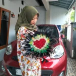 Round buket mawar merah bentuk love di Purwokerto dengan wrapping hitam dan aksen hologram.