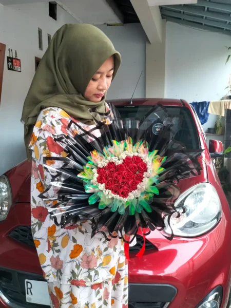 Round buket mawar merah bentuk love di Purwokerto dengan wrapping hitam dan aksen hologram.
